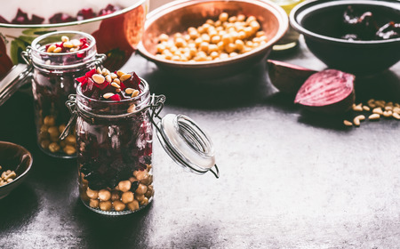 Healthy homemade beetroot salad with chickpeas and pine nuts in glasses for lunch on dark kitchen table background with ingredients, top view. Purple vegetables eating. Clean dieting food.の写真素材