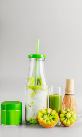 Healthy vegan layered matcha latte drink in bottle with drinking straw standing on table at light gray background. Matcha espresso. Clean eating, detox beverage, dairy food concept. Summer drinksの写真素材