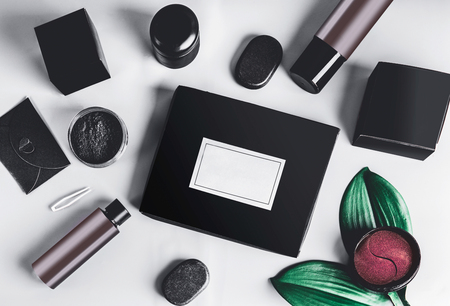 Black beauty box and various black and brown cosmetic product in jars and bottles with branding mock up.  Eye patch. Snail mucin or charcoal cosmetic set. Facial skin care . Blog promotion. Flat layの写真素材