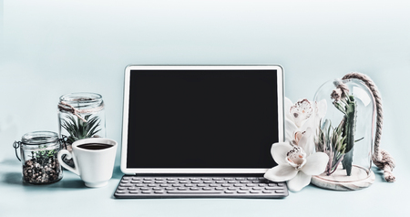 Blank screen modern laptop computer with succulent plants in glasses and orchid flowers on table.  Home female business office workspace.  Black blank screen for your designの写真素材