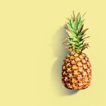 Pineapple at yellow background. Summer tropical fruits concept. Copy space for your designの写真素材