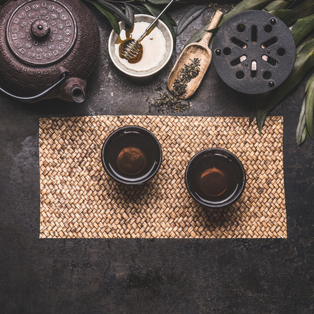 Traditional Asian green tea setting with black iron teapot, cups, candle and honey on dark rustic background with copy space, top viewの写真素材
