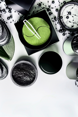 Facial cosmetic products setting in black and brown packaging. Natural cosmetics. Modern skin care with eye patches and charcoal powder on light background, top view with copy space. Beauty conceptの写真素材
