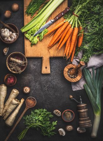 Various organic farm vegetables on dark rustic table with kitchen utensils, herbs and spices, top view. Frame. Copyspace. Vegan and vegetarian food concept. Healthy cooking lifestyleの写真素材
