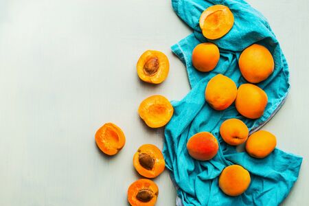 Fresh ripe apricots strew  on blue napkin at light mint background, top view Seasonal fruits harvest. Healthy clean eating conceptの写真素材