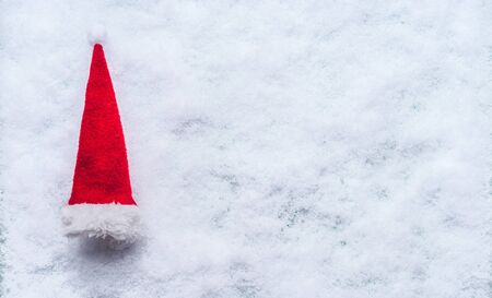 Santa hat on snow background. Christmas concept.  Flat lay . Copy spaceの写真素材