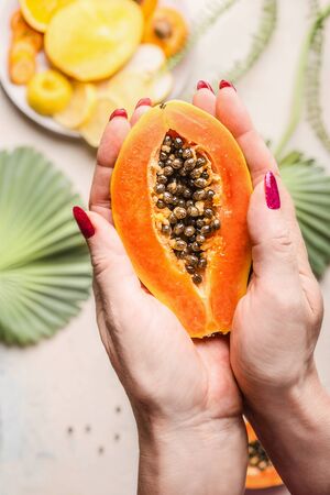 Female hand holding half papaya with seeds, top view close up. Healthy food. Exotic fruitsの写真素材