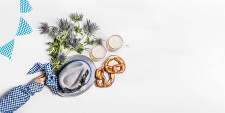 Oktoberfest background .  Mugs of beer, Bavarian hat with feather, pretzel, woman hand in traditional blue blouse and alpin flowers. Top view. Modern. Flat lay. Copy spaceの写真素材