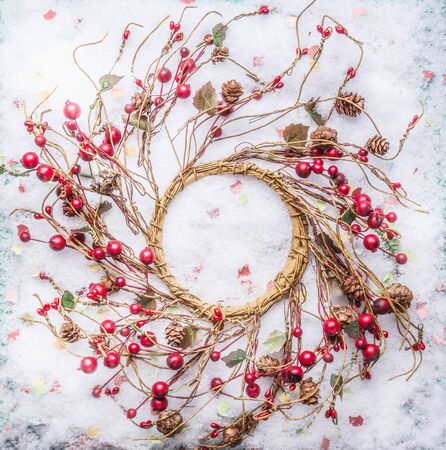 Christmas wreath with red berries on snow, top view.の写真素材