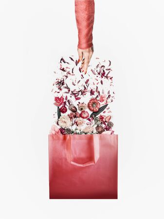 Autumn minimal concept . Shopping bag with autumn flowers and fall leaves arrangement and female hand in red pullover on white background. Creative layout. Autumn shopping with discounts. Sales.の写真素材
