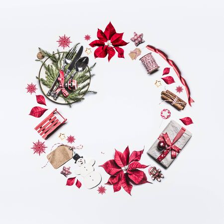 Christmas frame composition made with festive decoration objects lake Christmas wreath on white background , top view. Flat lay. Festive  layout with poinsettia, gift box, festive table settingの写真素材