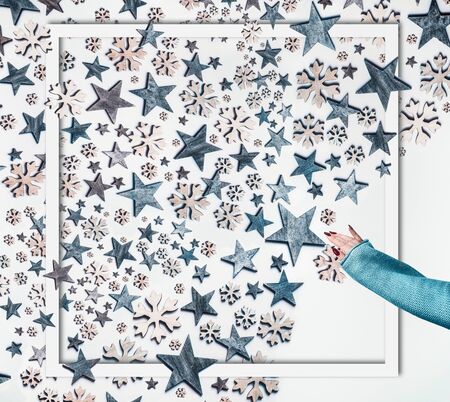 Winter holidays concept. Woman hand in knitted sweater make blue stars and decorative snowflakes...