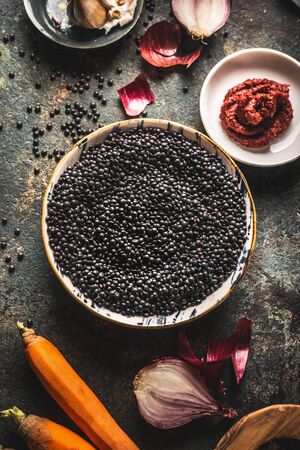 Close up black lentils in bowl with ingredients for delicious cooking.  Top view. Copy space. Healthy food. Protein rich vegan foods. Plant based protein  sourceの写真素材