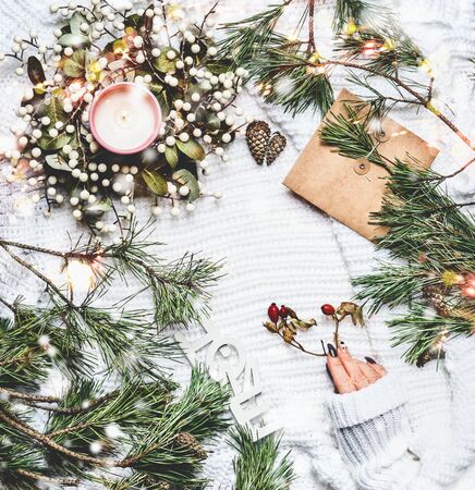 Female hand in warm knitted sweater on white plaid  with pine branchesの写真素材