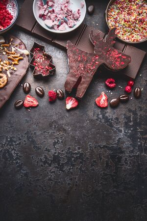 Christmas sweet gifts. Various chocolate in shape of Christmas symbols: Christmas tree, deer on dark  with copy spaceの写真素材