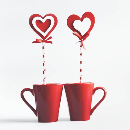 Two red mugs with hearts lollipop standing on white background. Declaration of love and Valentines day conceptの写真素材