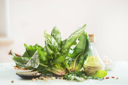 Fresh organic spinach bunch with olives oil bottle lies on kitchen table at light background. Healthy cooking conceptの写真素材