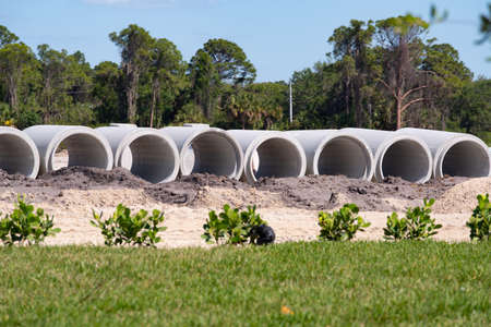 Concrete pipes for the construction of objects lie on the ground indusrty