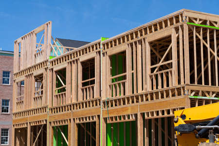New residential construction home framing against a blue sky under building plank