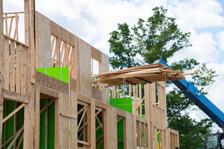 forklift at a construction site of a plywood house wood new frame up framework residental building