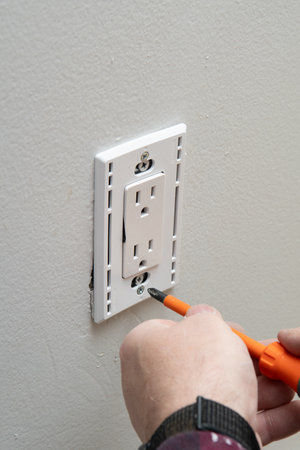 close up of man installing electrical outlet in wall in room of house new plug voltage