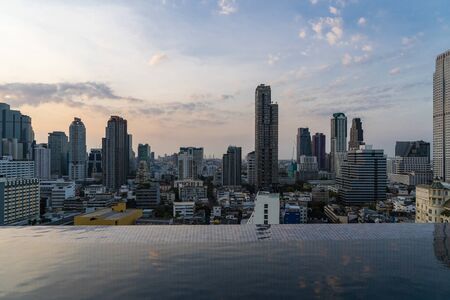 Aerial cityscape of picturesque Bangkok at sunset from rooftop swimming pool view. Panoramic sunrise skyline of the biggest city in Thailand. The concept of metropolis.の写真素材