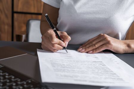 Close up of unrecognizable businesswoman signing contract at office table. Concept of CEO work and...
