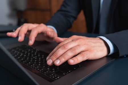 A man in suit typing the contract on laptop. The concept of entering into legal power to take liabilities. Formal wearing.の写真素材