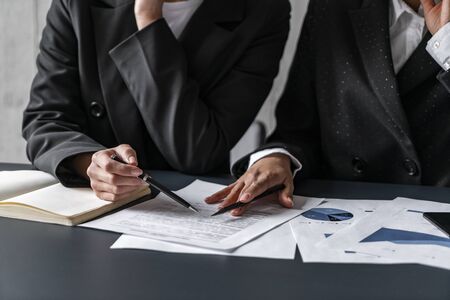 Hands of diverse businesswomen working with documents in office. Concept of legal work and business collaborationの写真素材
