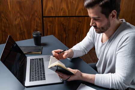 Good looking Man taking notes on work hours. Concept of day planning.の写真素材