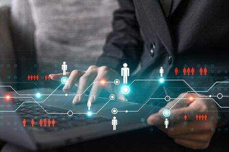 Businesswoman typing on laptop in office. Social network icon hologram. People connection concept. Double exposure.の写真素材