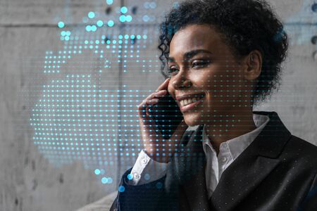 Businesswoman speaks phone and world map hologram. Double exposure.の写真素材