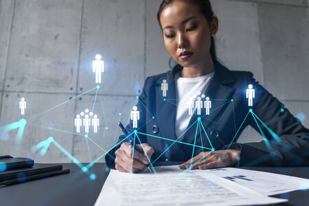 A woman signs contract and social network theme hologram. Double exposure.