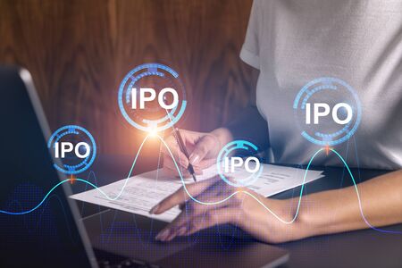 Businesswoman typing on computer in office. IPO icon hologram. Double exposure.の写真素材