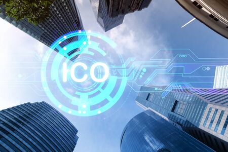 ICO icon hologram on low, wide angle view of glass and steel contemporary skyscrapers in financial...