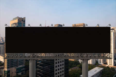 Blank black road billboard with Bangkok cityscape background at sunset. Street advertising poster, mock up, 3D rendering. Front view. The concept of marketing communication to promote or sell idea.の写真素材