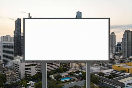Blank white road billboard with Bangkok cityscape background at sunset. Street advertising poster, mock up, 3D rendering. Front view. The concept of marketing communication to promote or sell idea.の写真素材