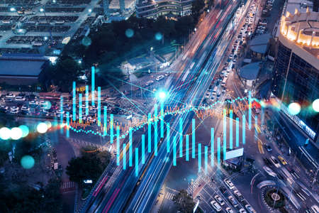 FOREX and stock market chart hologram on aerial view of road, busy urban traffic highway at night. Junction network of transportation infrastructure. The concept of international trading.の写真素材
