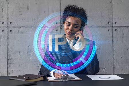 Businesswoman speaks phone and ipo icon hologram. Double exposure. Initial primary offering invest concept.の写真素材