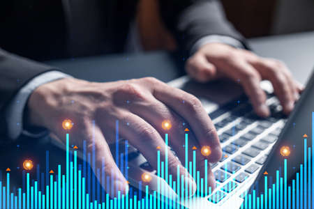 Businessman trading on-line, typing laptop background and financial graph hologram.