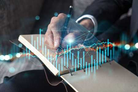 Businessman in suit taking notes. Multiexposure with forex graph hologram. Man writing down...