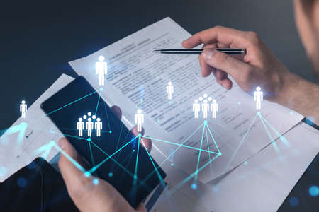 Double exposure of man signing contract with phone and social network icon hologram. Concept of...