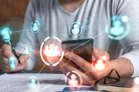 Double exposure of man signing contract with phone and social network icon hologram. Concept of...