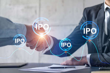 Multiexposure of two businesspeople handshake and initial primary offering, IPO hologram drawing...