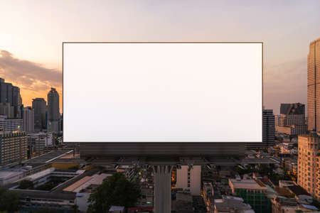 Blank white road billboard with Bangkok cityscape background at sunset. Street advertising poster, mock up, 3D rendering. Front view. The concept of marketing communication to promote or sell idea.の写真素材