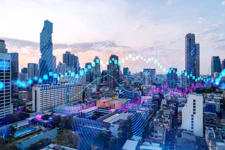 Glowing FOREX graph hologram, aerial panoramic cityscape of Bangkok at sunset. Stock and bond...
