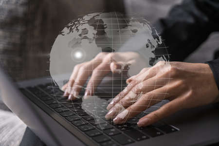 Businesswoman typing on laptop in office. Planet earth world map hologram. International business...