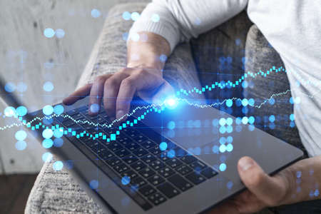 Man typing on laptop background and financial chart drawing. Multiexposure.