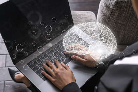 Businesswoman typing on laptop in office. Brain network illustration hologram.の写真素材