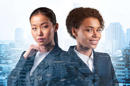 Two young attractive businesswoman in suits dreaming about new career opportunities after MBA graduation. Concept of multinational corporate team Bangkok on background. Double exposure.の写真素材